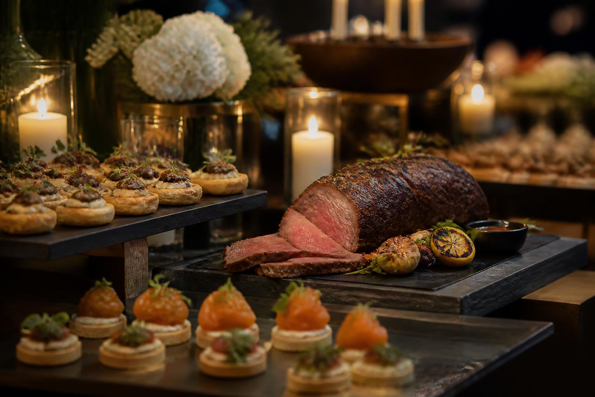Elegantes Catering-Buffet mit Canapés und Roastbeef bei stimmungsvollem Kerzenlicht
